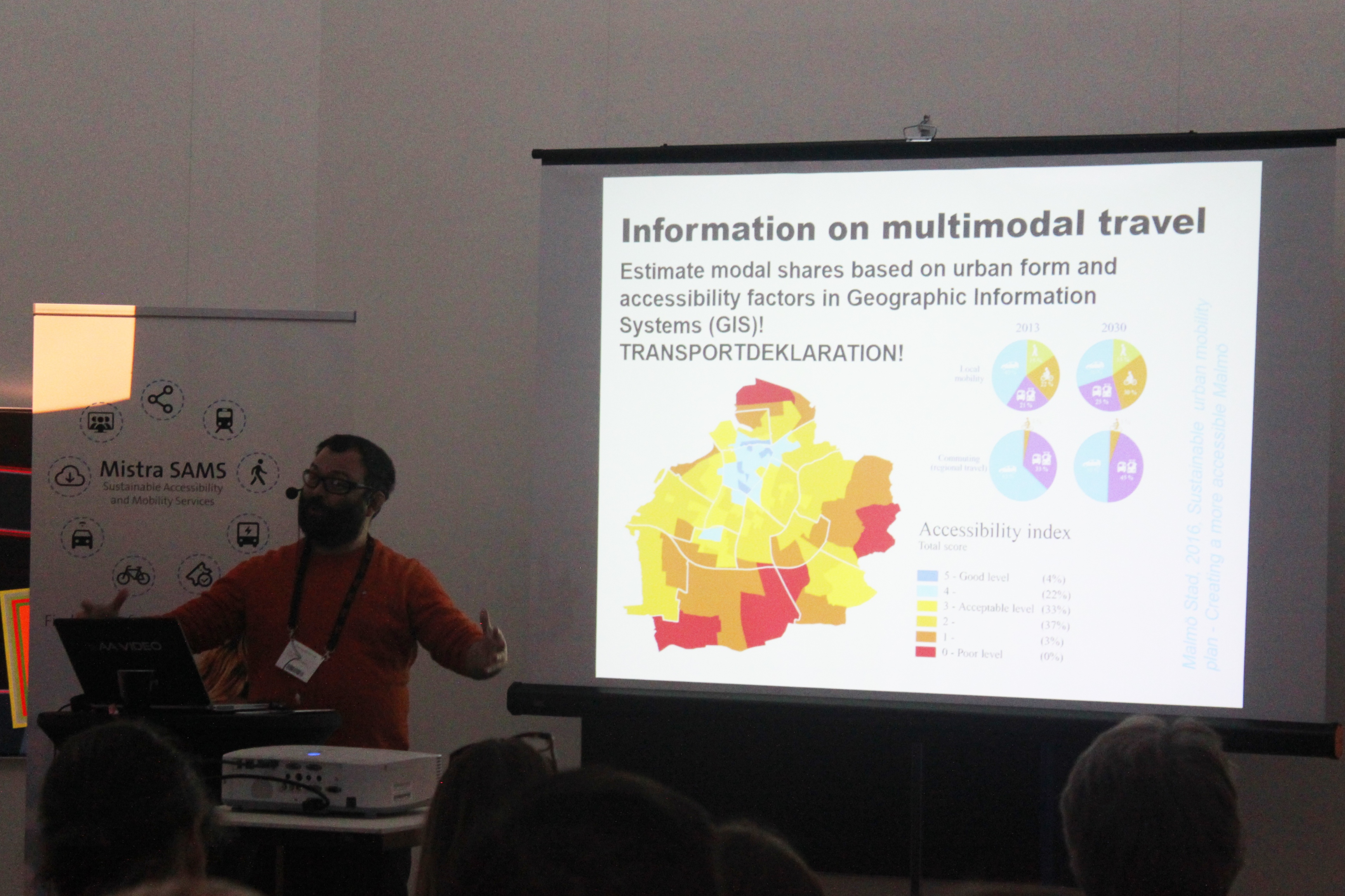 A person holding a presentation, the current slide shows a map with different parts in yellow, red and orange.